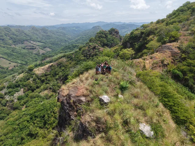 A small group on top of the Peñón K59, seen from a drone, with green mountains all around
