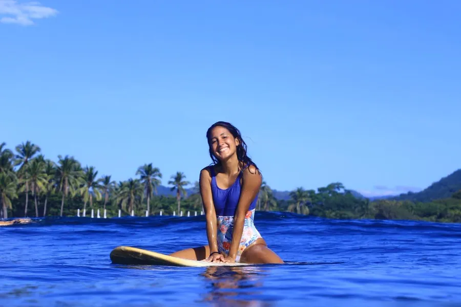 Melissa from Alegria Trips smiling on her surfboard in the ocean in El Salvador