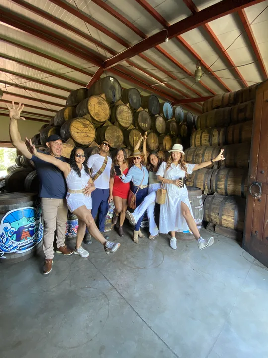 A happy group of travelers among rum barrels at the Cihuatán distillery