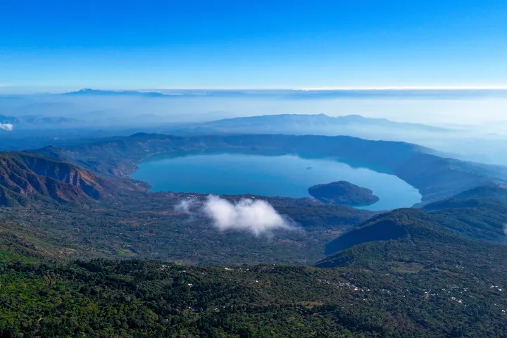 Aerial view of Lake Coatepeque surrounded by green mountains